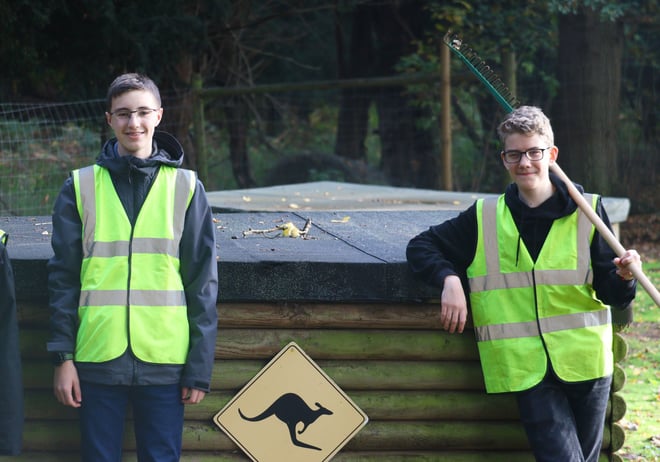 Boys pose in front of wallaby sign with cleaning tools 