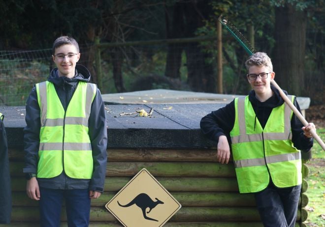 Boys pose in front of wallaby sign with cleaning tools