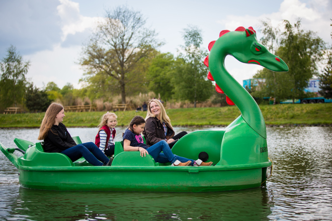 Family enjoy a ride on green dragon pedlo boat on lake 